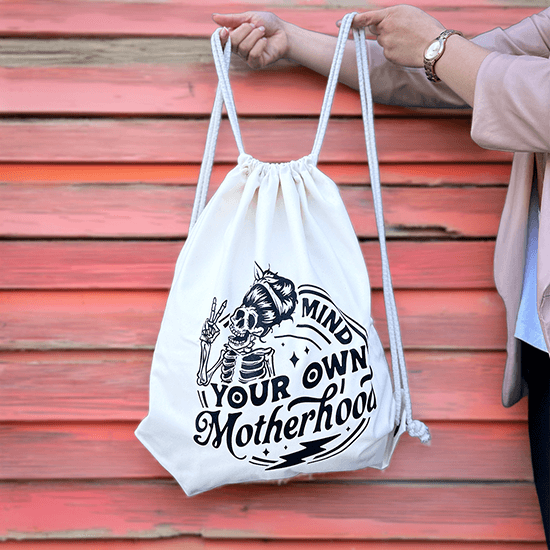 Bawełniany worek z nadrukiem kościotrupa mamy w zabawnym stylu oraz napisem Mind Your Own Motherhood, idealny dla świadomych i pewnych siebie mam